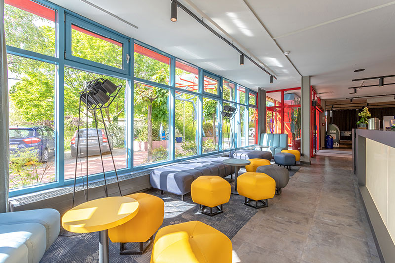 The lobby of a&o Berlin Kolumbus showcases natural light and green surroundings.