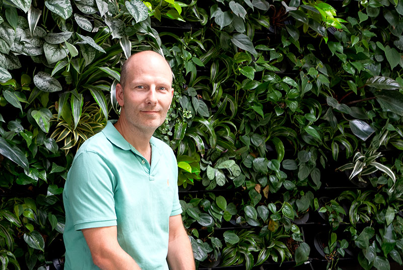 Oliver Winter, CEO of a&o Hostels, standing in front of a green wall